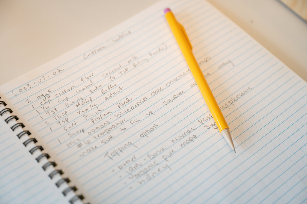 Handwritten paleo waffle recipe in a notebook dated 2023-07-01 with a yellow pencil resting on the page.