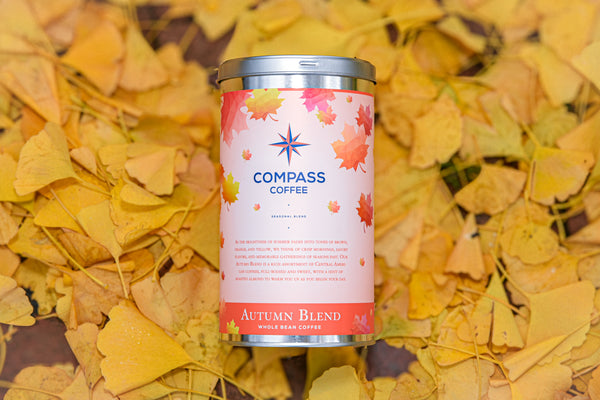 Compass Coffee Autumn Blend packaging surrounded by golden fall leaves