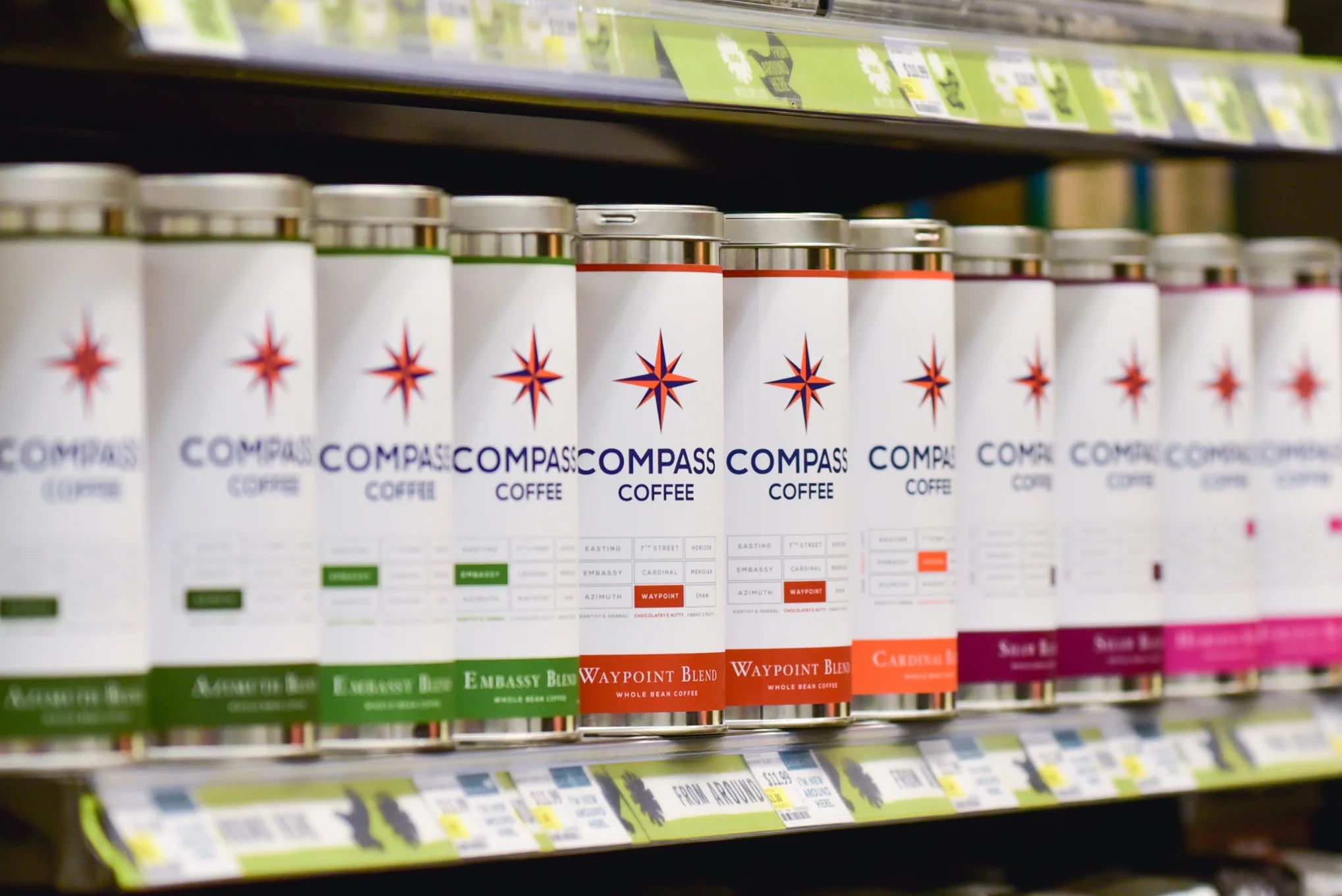 Different flavors of Compass Coffee blends lined up in a shelf.