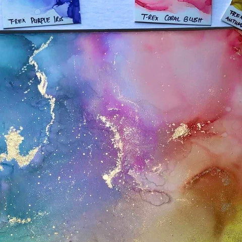 Artist @artsy_livey painting with alcohol ink swatches next to it