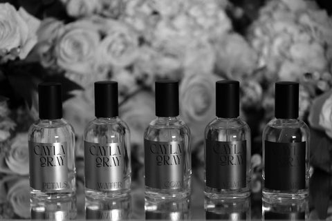 Perfumes in a row in front of flowers