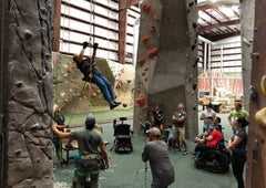 A female Adaptive climber ascends during a Paradox Sports triaining session at ProjectRock Climbing Gym