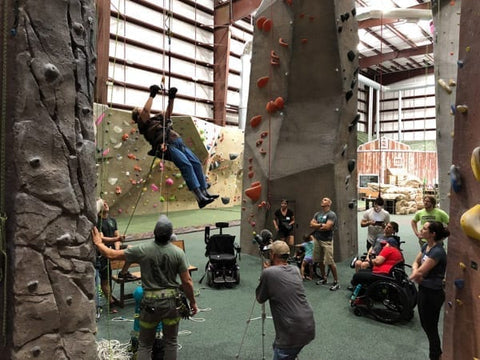 A female Adaptive climber ascends during a Paradox Sports triaining session at ProjectRock Climbing Gym