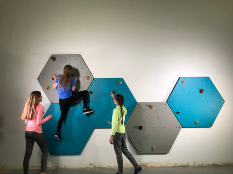 three kids playing on a climbing wall