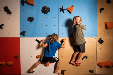 two kids climbing on a home climbing wall