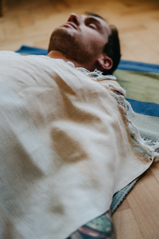 Shavasana pose-man resting after yoga practice covered with natural blanket