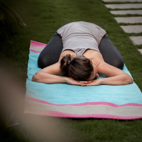 Balasana yoga pose done on cotton yoga mat in the garden