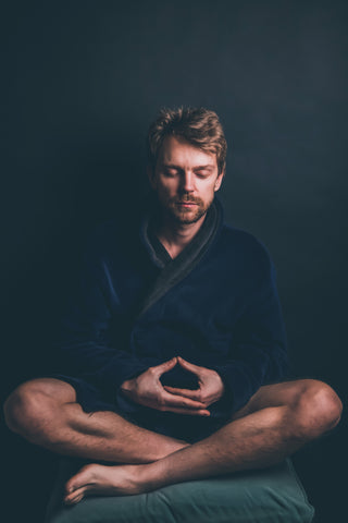 man meditating on yoga rug in peaceful environment