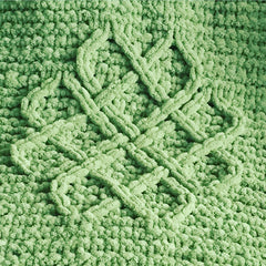 A close up of knitting detail showing green chenille yarn with a Celtic love knot design.