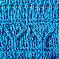 Close up of knitting detail showing blue chenille yarn in a southwest design.