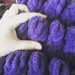 Close up of knitting detail showing purple yarn in a bubble design.