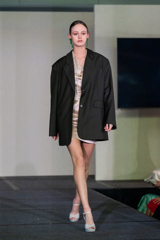 Le Reussi Fashion show with model walking in an oversize green blazer with a mini dress