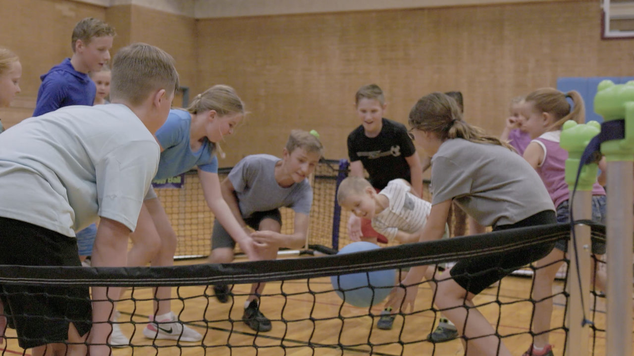 Kid striking ball in gaga ball pit in school gym for pe class