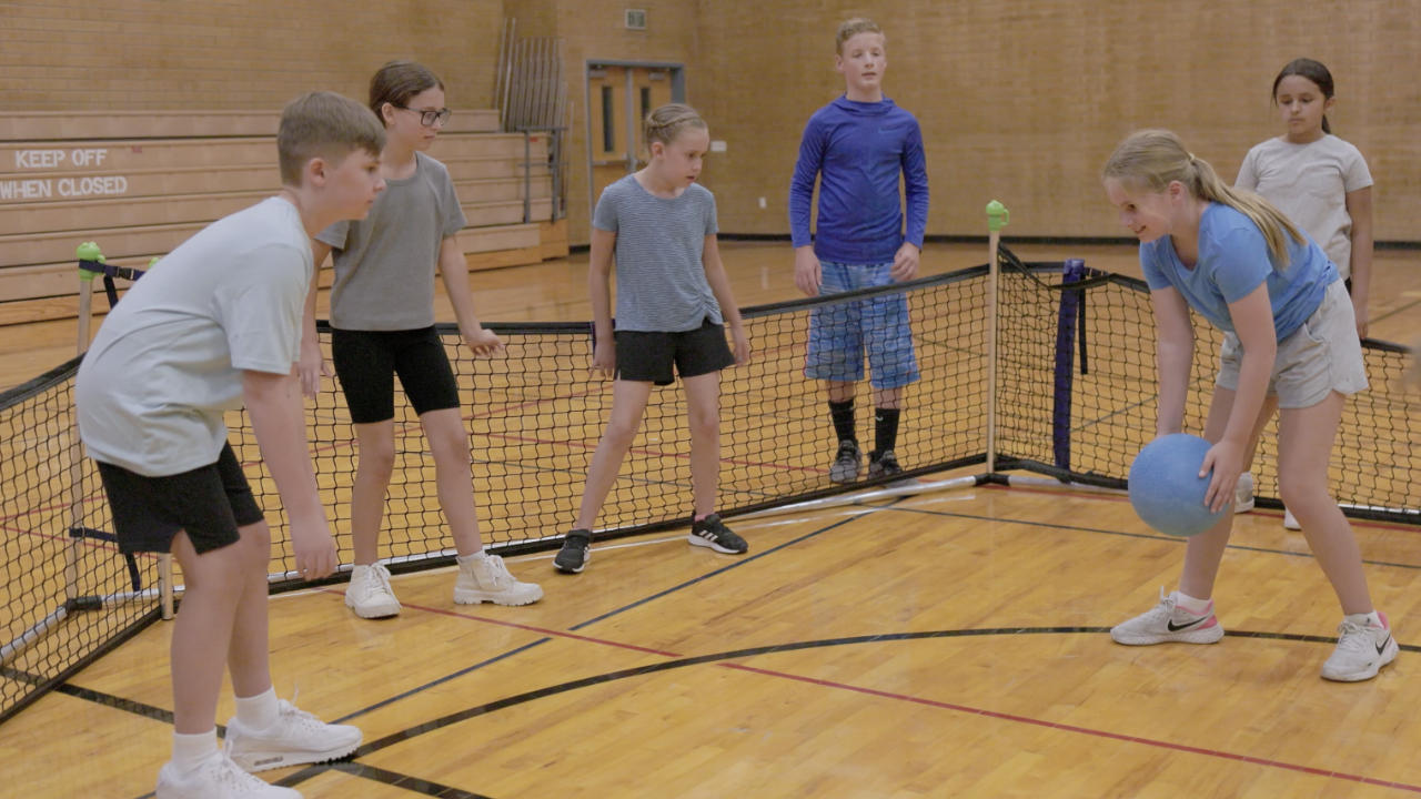 Kids playing grab and roll gaga ball and a girl is ready to roll the ball