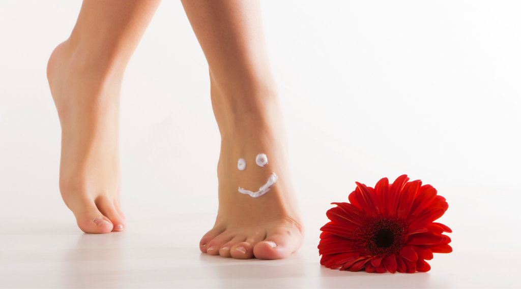 feet with a smiley face drawn with lotion and red flower