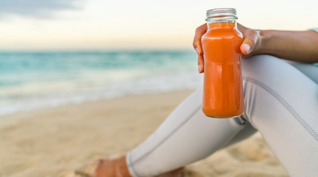 lady holding carrot juice at the beach