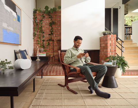 man sitting on a chair with white sonos era 300