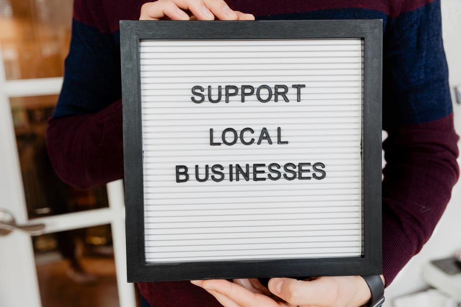 person holding a sign reading support local businesses