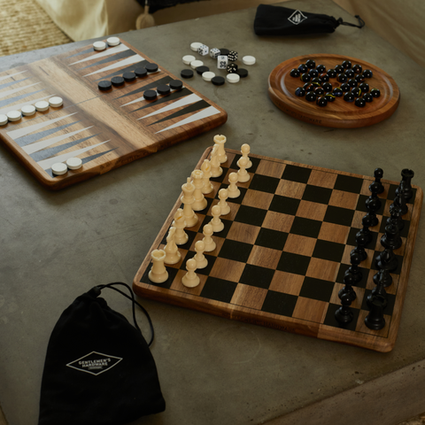Chess Board on concrete table with other wooden games surrounding it