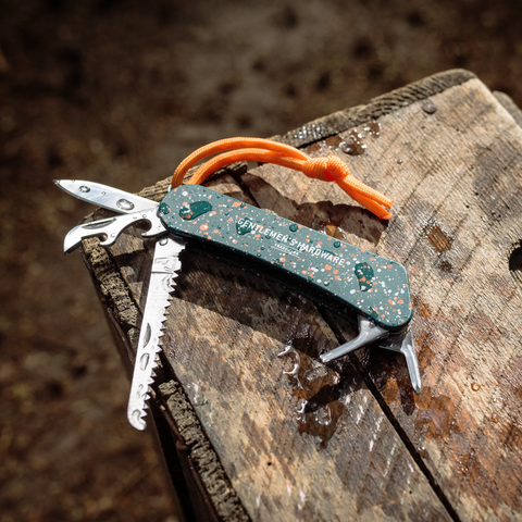 Wilderness Multi Tool with stainless steel tools open on wood background