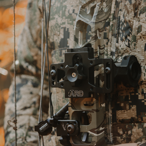 Mathews Archery V3 bow with an Adjustable Red Dot bow sight and a man in Sitka Gear.