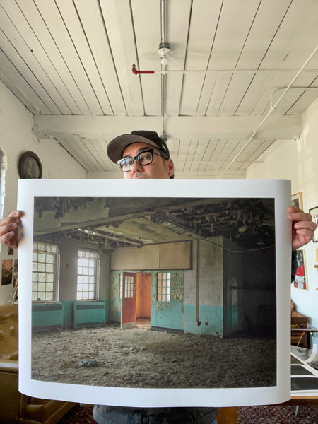 someone holding a photographic print of the abandoned mental hospital 