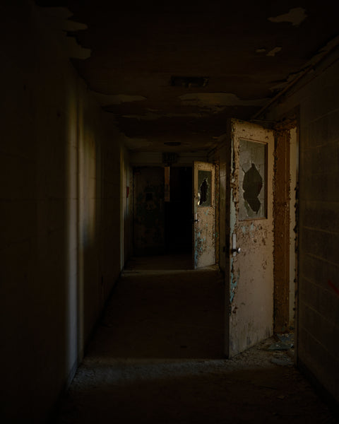 open doors and dark hallway in the abandoned mental institution 