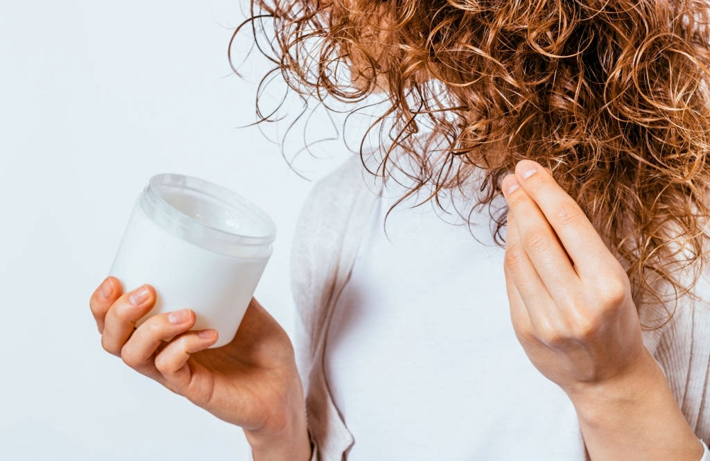 lady is applying hair conditioner to her brown hair