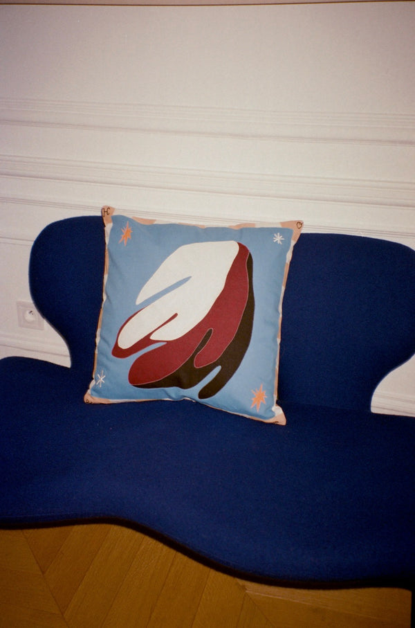 The cushion is displayed on a blue sofa. | © Pangea 2024