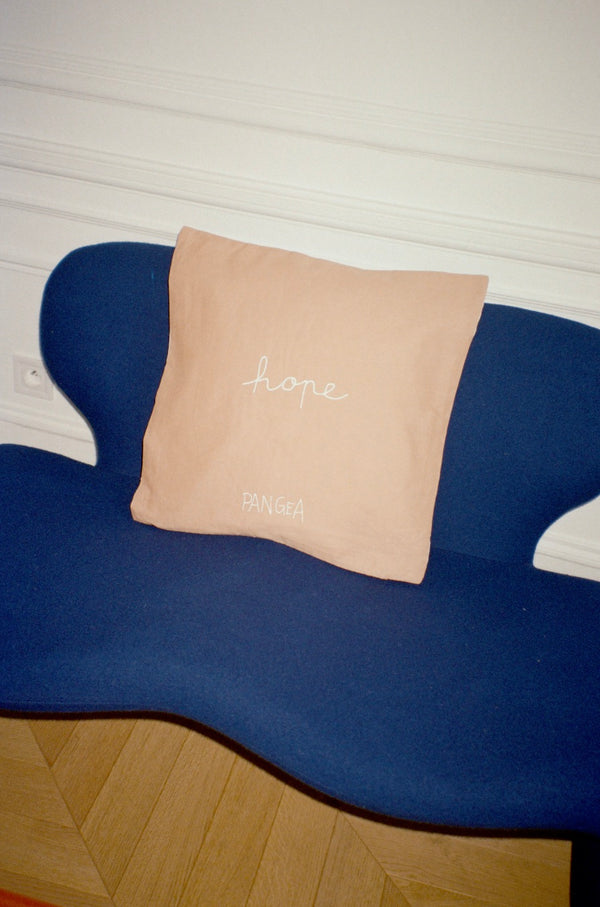 The cushion is displayed on a sofa, this time showing the reverse side of the cushion. | © Pangea 2024