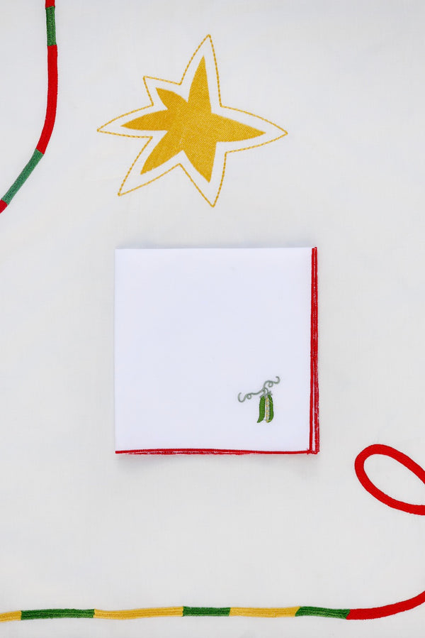 This napkin has two small green beans embroidered in the corner.  | © Pangea 2024