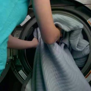 woman putting cover for the best air bed into washing machine