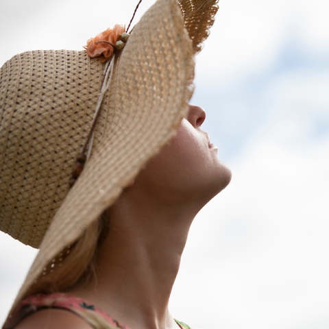 Woman in sun hat looking up at the sky