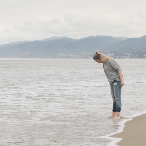 Woman wading in ocean on cloudy day