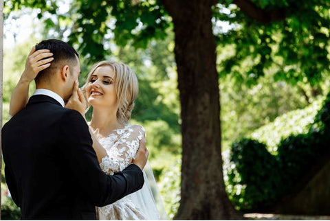 A newlywed couple standing underneath a tree