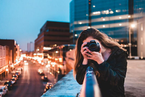 A woman shooting with her camera in a city