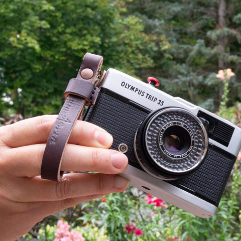  An Olympus film camera with a Due North Leather finger strap attached.