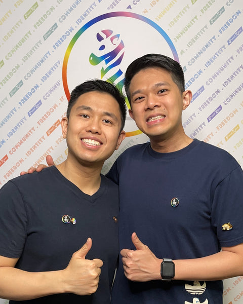 2 lgbtq+ men standing infront of a proud zebra banner