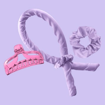 A pink hair scrunchie, measuring tape, and headband against a purple background.