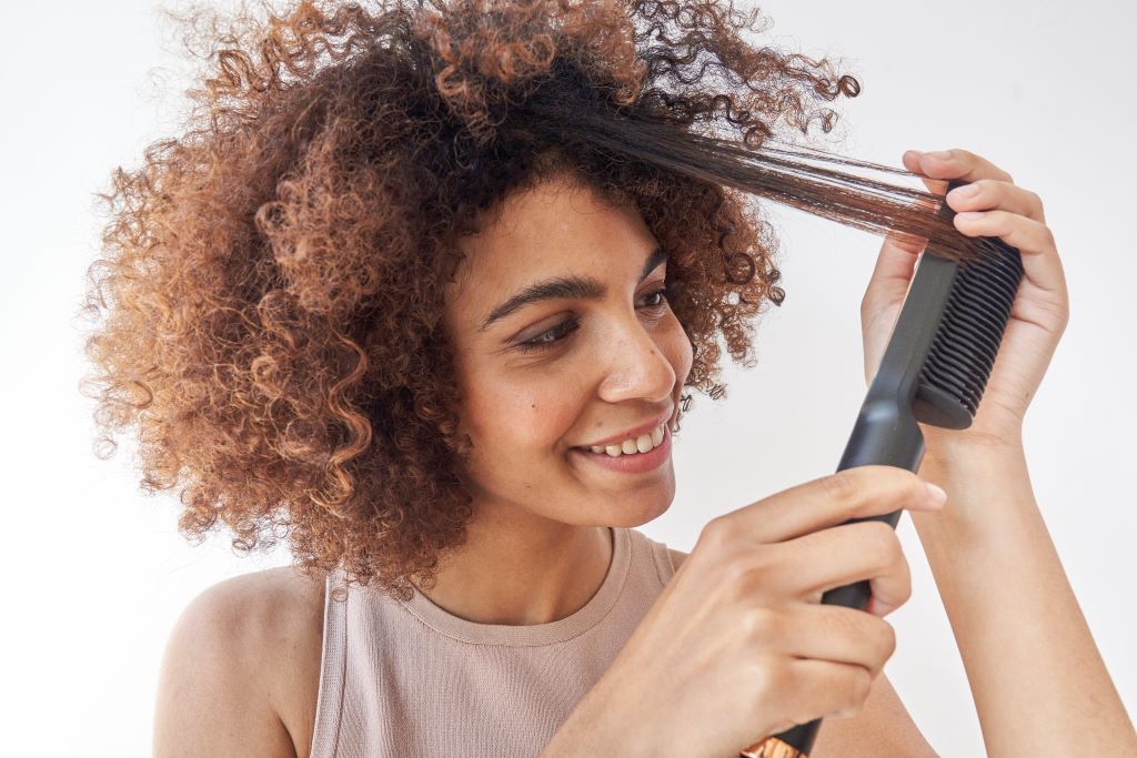 Mulher com cabelo crespo alisando com a escova Basiqe Sleek Gold