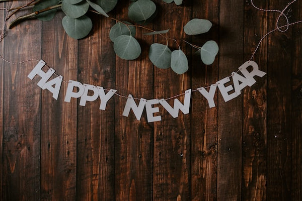 Photo by Kelly Sikkema of Happy New Year on a wooden background with Eucalyptus framing the image