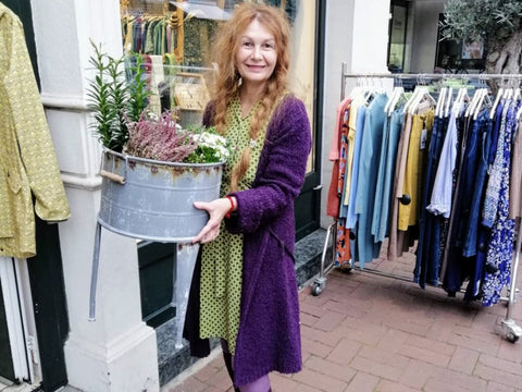 Frau auf Bild hält Blume NOA NOA Boutique Vicci und PEARLS OF AFRICA