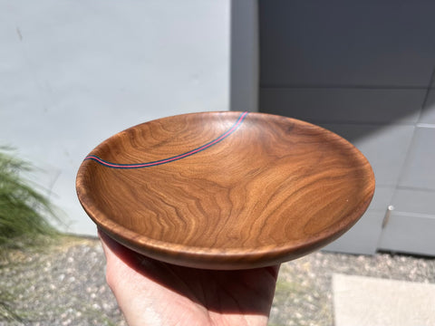 Hand holding walnut bowl with blue and pink stripe