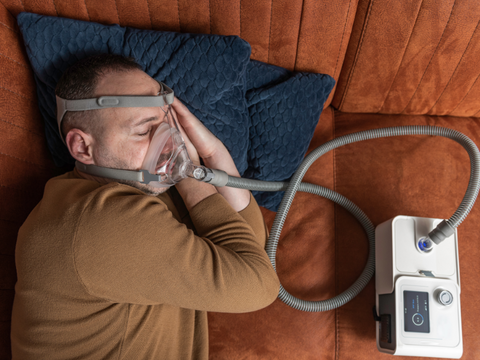 Man sleeping on bed with cpap sleep apnea machine