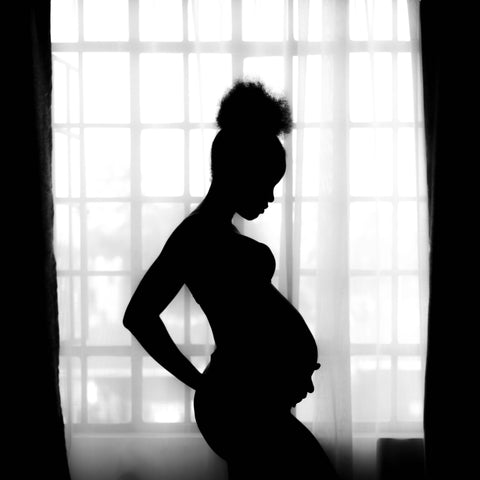 silhouette of a pregnant woman standing in front of a window