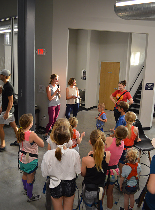 Image showing Nicole Carr, founder of Blind Spot, speaking to young climbers at event.