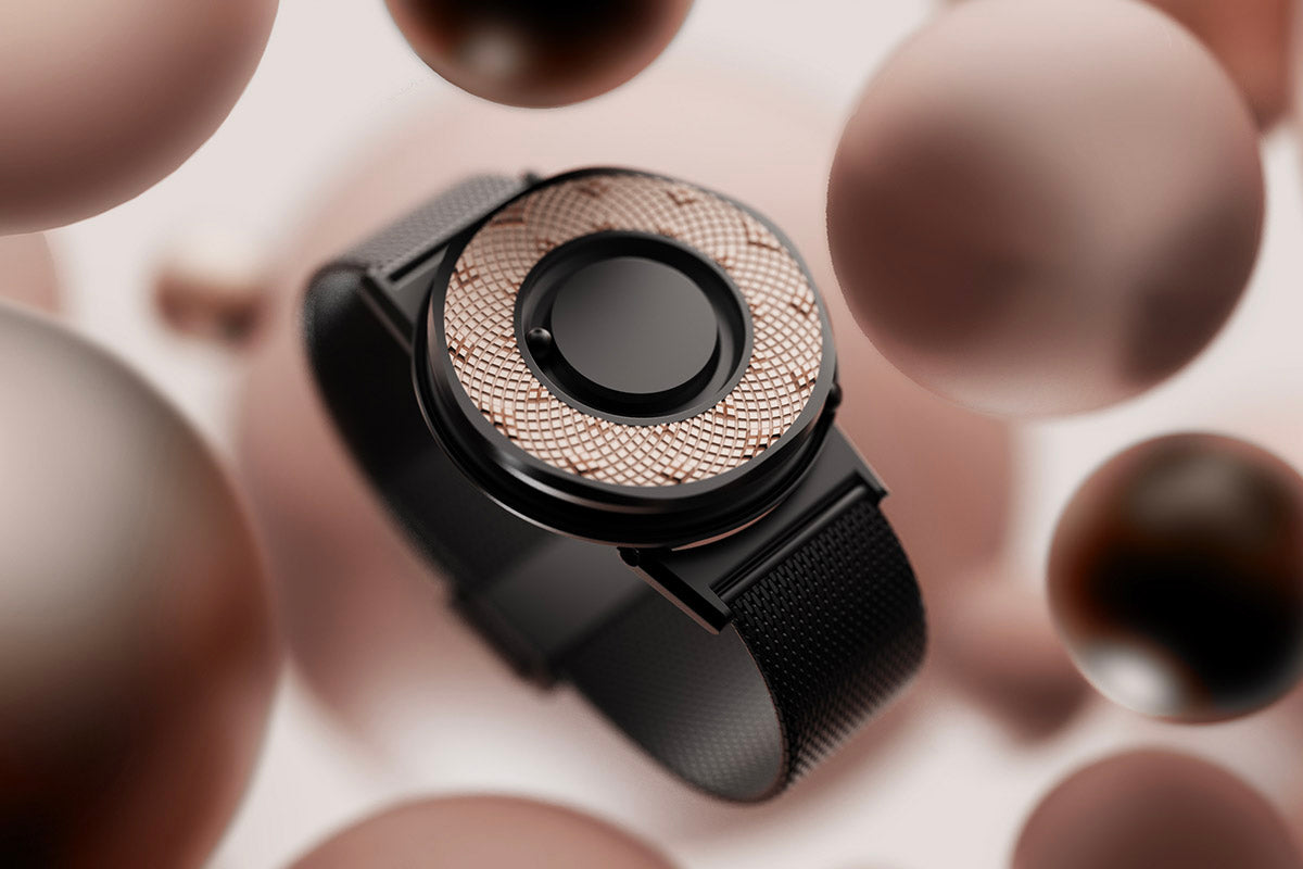 A render showing the Eone Switch in black floating against large clay brown spheres. The Switch has the rose gold Sunflower Ring fitted.