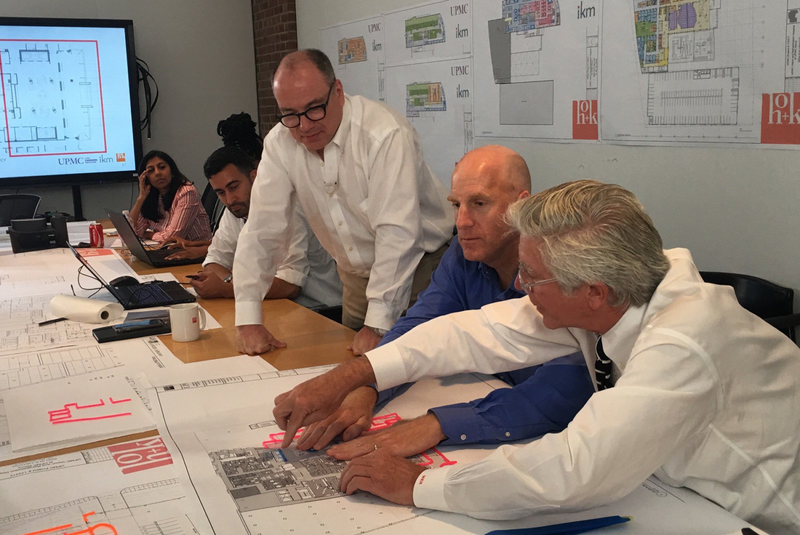 Chris discusses plans with HOK Architects in a group meeting.