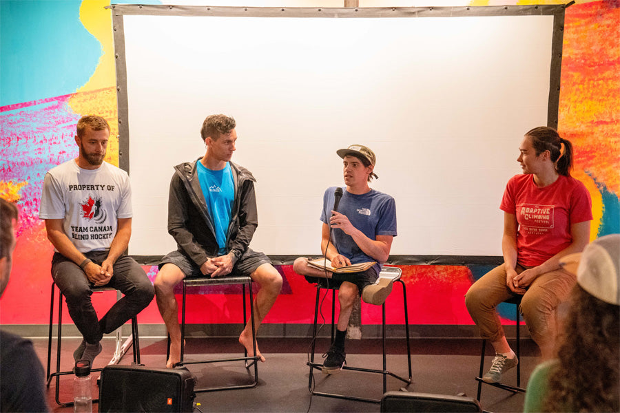 Four individuals sit in front of a projector screen. From left to right: Chaz Misuraca, Justin Salas, Ben Mayforth, Seneida Biendarra – all four are professional paraclimbers. They discuss the importance of accessibility and inclusion in climbing and daily life.