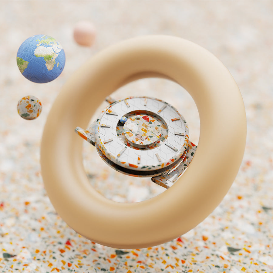 Image shows an abstract visual render of the Bradley Timepiece; made from recycled plastic waste from the Ocean, fashioned into a multicoloured terrazzo pattern. Orbiting the timepiece is Earth and a smaller planet, also made from recycled plastic. The timepiece floats in space, passing through a large beige torus shape.